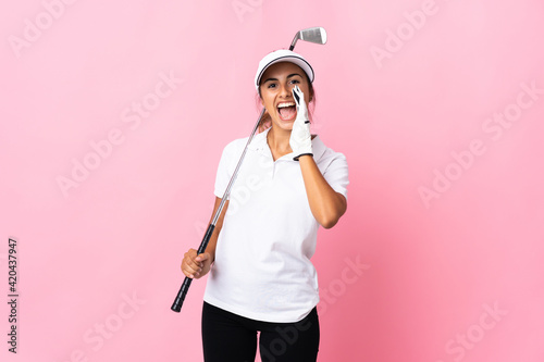 Young hispanic woman over isolated pink background playing golf and shouting with mouth wide open