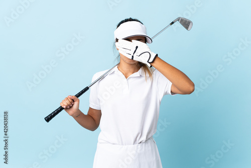 Young hispanic golfer woman over isolated blue wall covering eyes by hands. Do not want to see something © luismolinero
