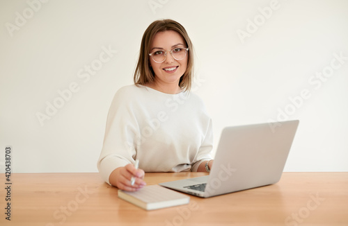 Happy young businesswoman working on netbook in office