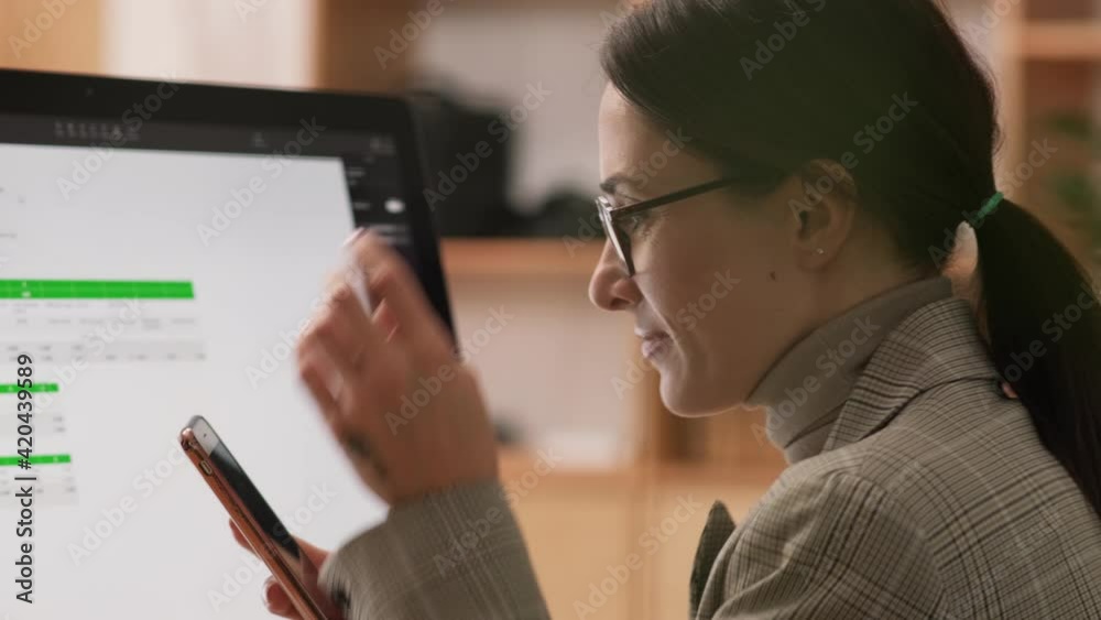 A positive businesswoman is working with her computer sitting in the office A positive businesswoman is working with her computer sitting in the office