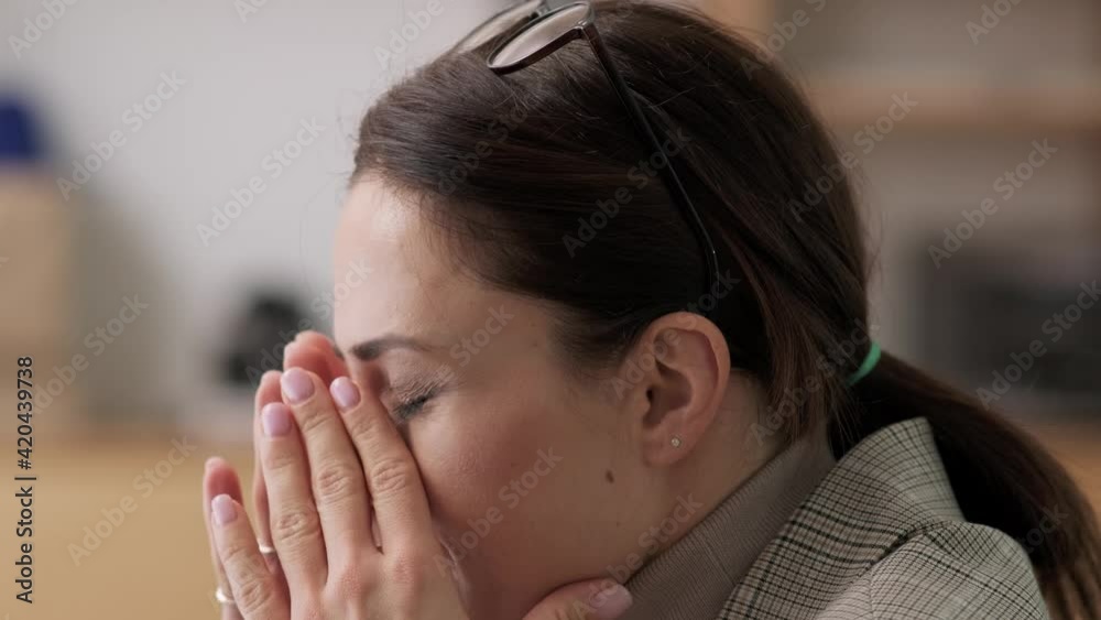 A close-up view of a tired businesswoman is massaging her temples while working using her computer sitting in the office A close-up view of a tired businesswoman is massaging her temples while working using her computer sitting in the office