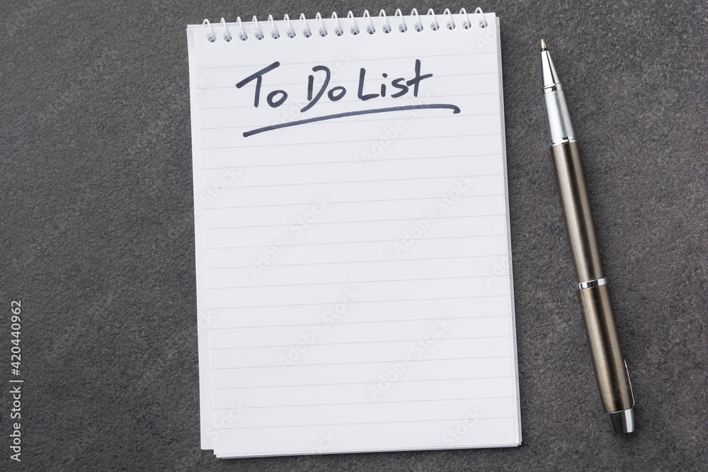 High angle view of a notepad with the to do list and a pen on grey desk 