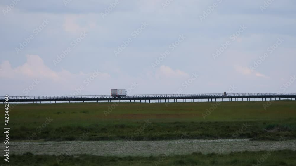 white van truck driving over a bridge from a distance telephoto shot white van truck driving over a bridge from a distance telephoto shot