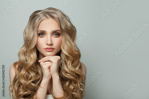 Young blonde woman with long healthy curly wavy hair on white background