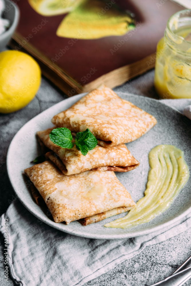 Crepes with homemade cottage cheese and lemon curd on a gray plate