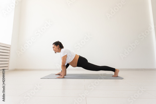 Purposeful pregnant woman exercises during yoga class and relaxes while sitting on a mat on the floor. Concept of physical and mental preparation of the body for childbirth. Place for text
