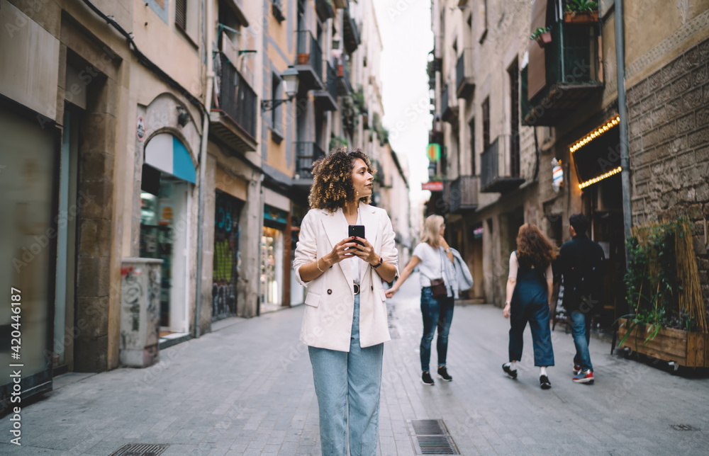 Trendy dressed travel blogger 20s exploring new city during getaway touristic vacations, Caucaisan hipster girl in stylish apparel using 4g wireless connecting on modern smartphone technology