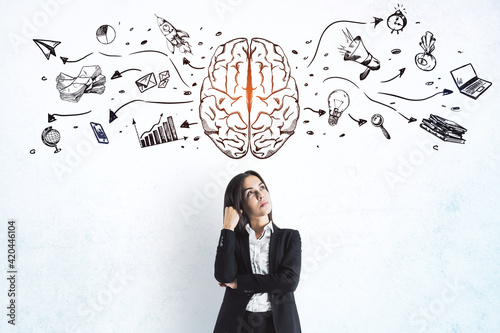 Left and right human brain concept with businesswoman on light wall background with painted sketch of business icons photo