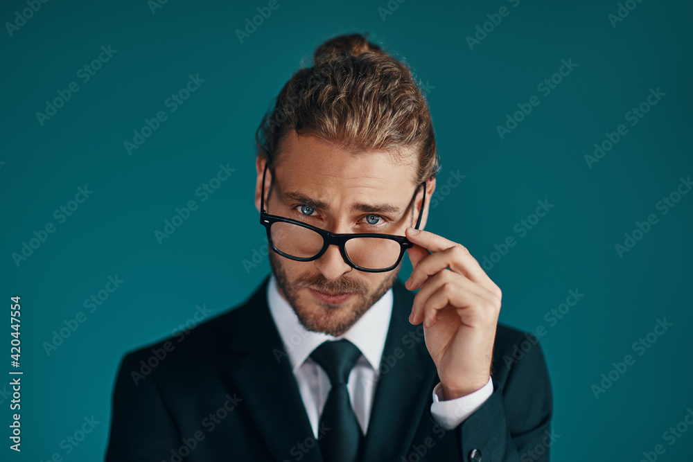 s young man in elegant suit looking at camera and adjusting eyewear while standing green background s young man in elegant suit looking at camera and adjusting eyewear while standing green background