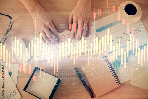 Multi exposure of man's hands typing over computer keyboard and forex graph hologram drawing. Top view. Financial markets concept.