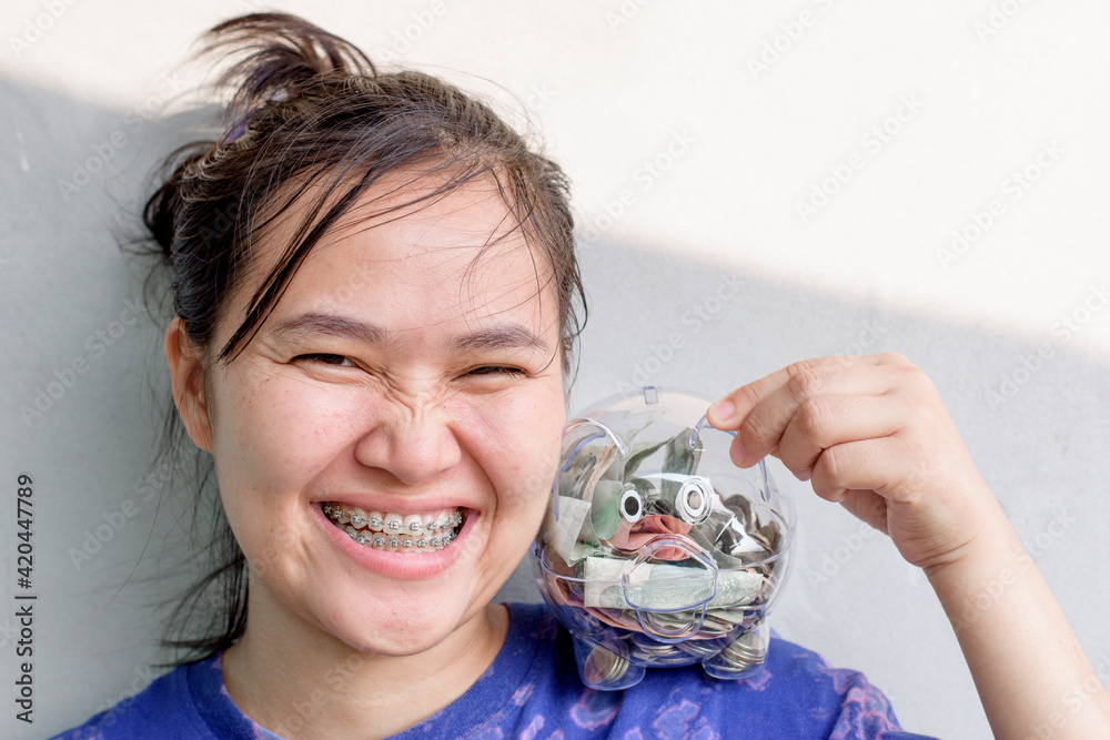 Asian woman puts a piggy bank on her shoulder Asian woman puts a piggy bank on her shoulder