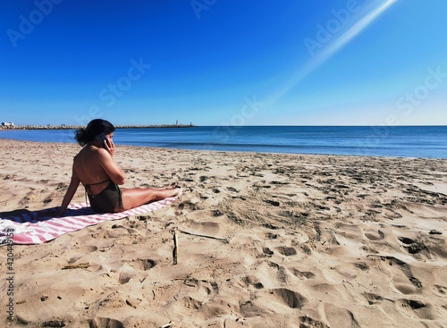 Middle age woman with mobile phone at the beach