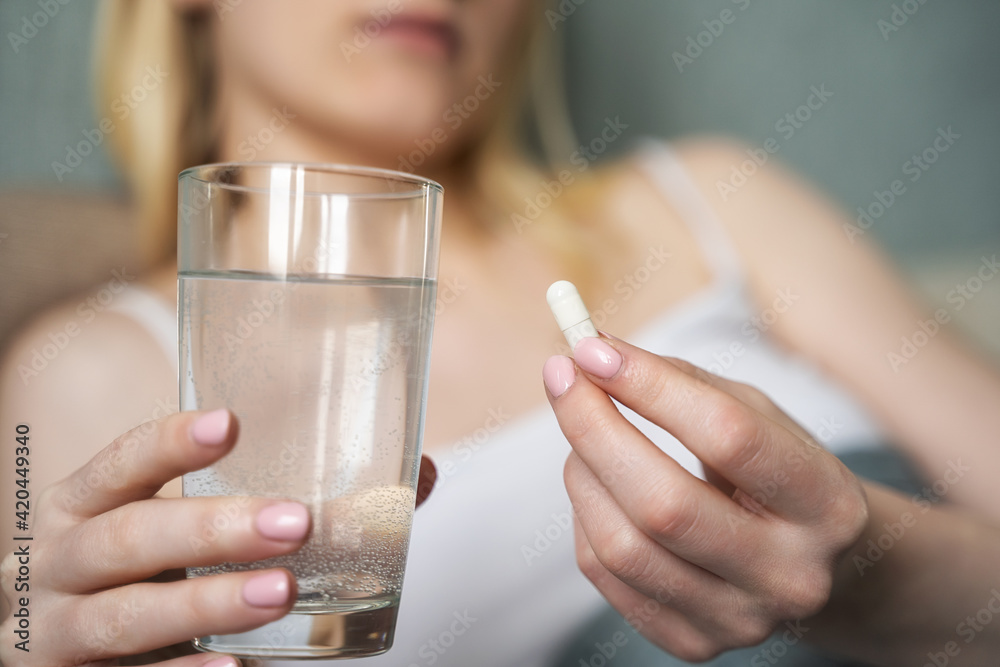 Closeup on pills pack in hand of ill young woman laying on sofa. Closeup on pills pack in hand of ill young woman laying on sofa.
