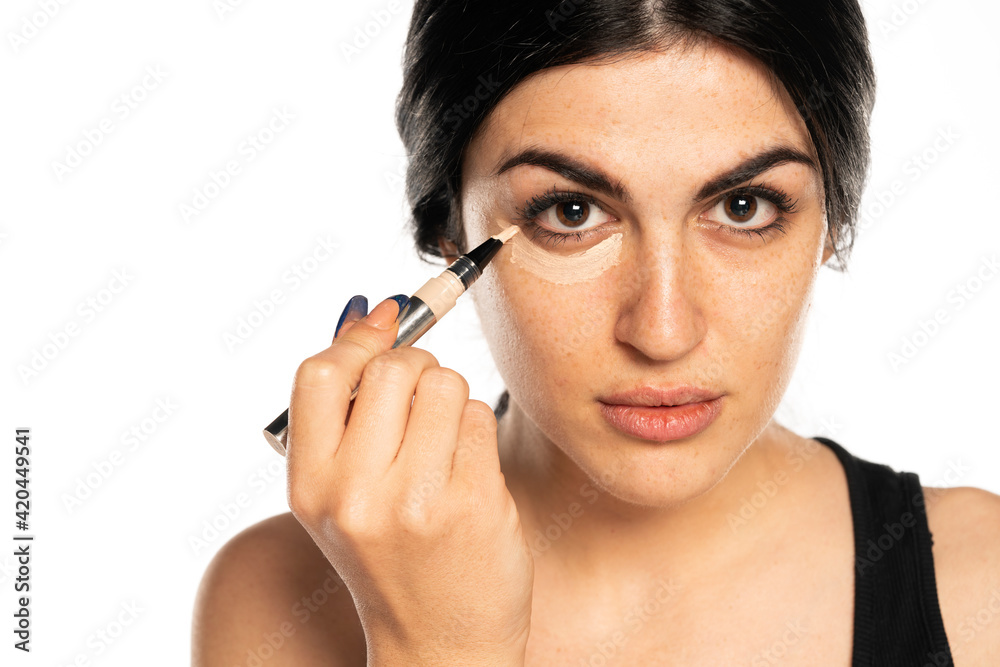Half portrait of young beautiful woman applying concealer Half portrait of young beautiful woman applying concealer