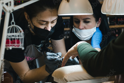 A manicure master teaches a colleague his profession in a cozy atmosphere of a nail service salon