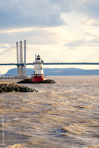Obraz na płótnie Tarrytown, NY - USA - Mar. 14, 2021: Vertical view of the Tarrytown Light, a sparkplug lighthouse on the east side of the Hudson River. Seen at sunset with the Mario M. Cuomo Bridge in the distance. w salonie