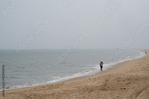 people walking along sand beach on sunny day. Holiday beach in Haikou city  Hainan province