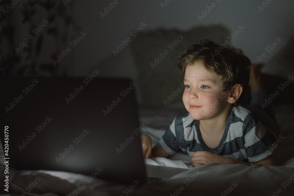 Little boy using laptop by night at home on the bedroom. Little boy using laptop by night at home on the bedroom.
