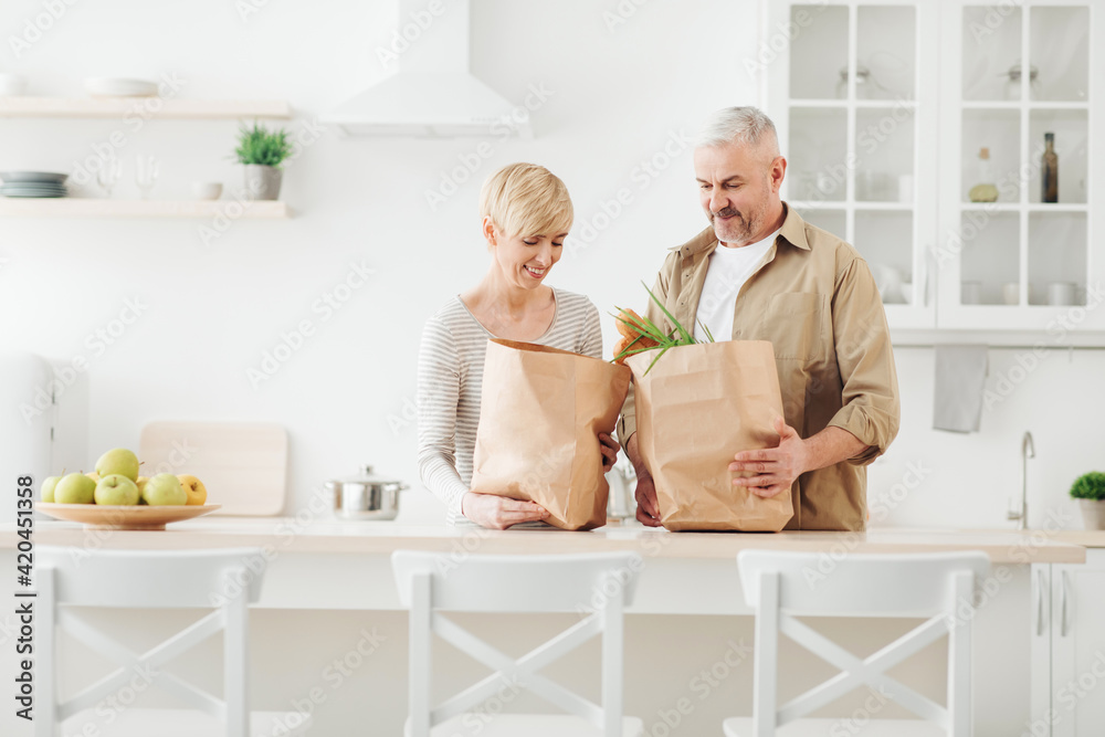 Chores, housekeeping, buying together at free time, couple unpacking fresh products from market in kitchen Chores, housekeeping, buying together at free time, couple unpacking fresh products from market in kitchen