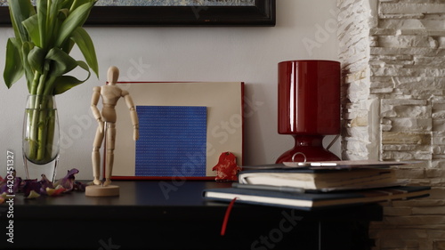 Komódka mebel w salonie z ramką czerwoną, karteczką kolorową i lampką szklaną bordową photo