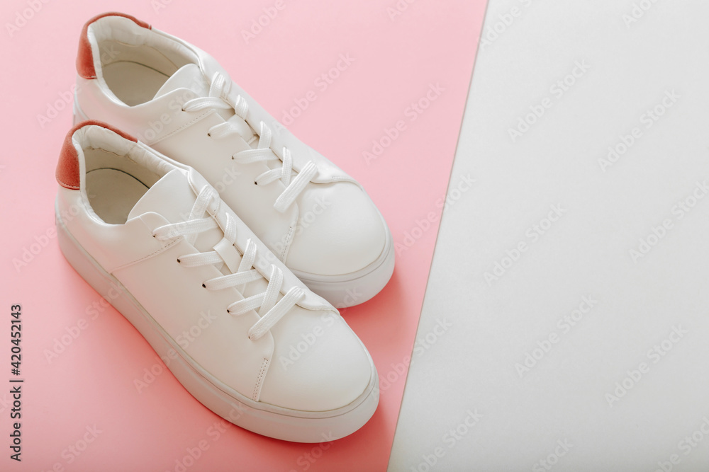 White sneakers on color pink background. Female white leather shoes with  laces on pink background with copy space. Pair of stylish sneakers  Comfortable sportswear hipster womens shoes. Stock 写真 | Adobe Stock