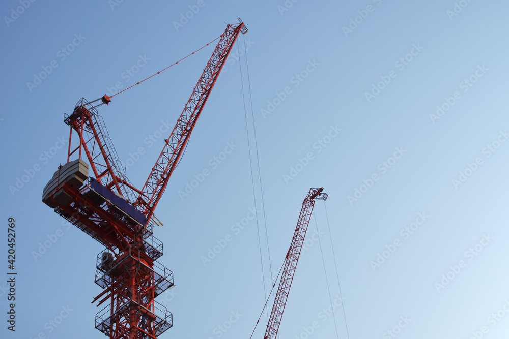 Cranes high-rise in, Construction site, On backdrop of blue sky and sunrise morning with copy space, Industrial machine engine and mechanical outdoor workplace. Cranes high-rise in, Construction site, On backdrop of blue sky and sunrise morning with copy space, Industrial machine engine and mechanical outdoor workplace.