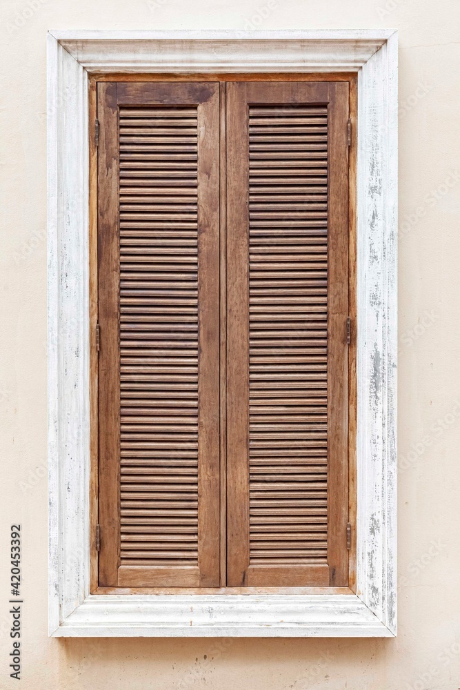 Fototapeta premium European antique brown wooden shutters window and white cement wall