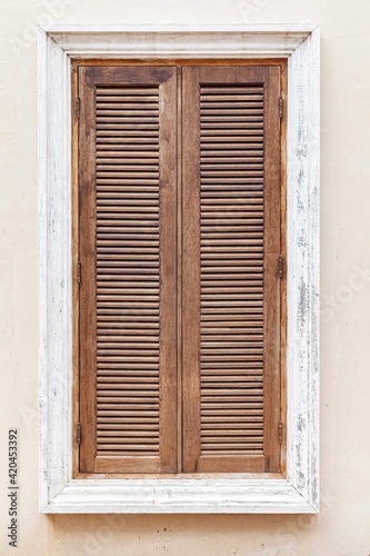 European antique brown wooden shutters window and white cement wall