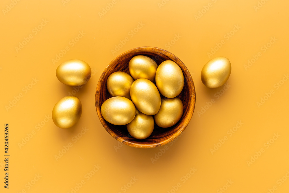 Golden Easter eggs in wooden bowl. Wealth and good luck concept.