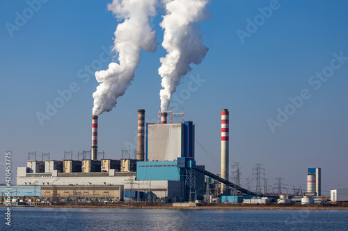 View of the coal-fired power plant located by the lake. Patnow  Polamd. Made on a sunny day. Deep blue sky.