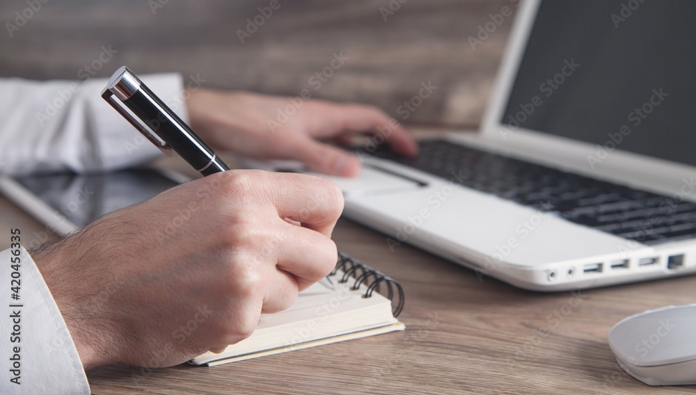 Man typing in keyboard and writing on notepad. Man typing in keyboard and writing on notepad.