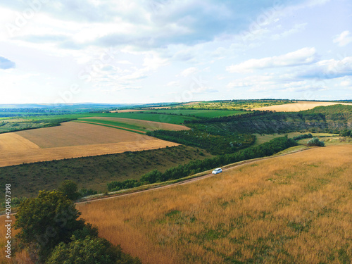 white car driving on road in fields