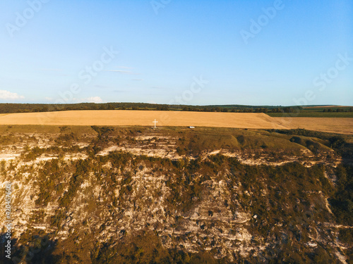 metal cross and white car on top of hill