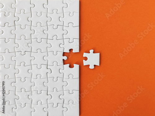 Missing piece of the puzzle, white puzzle pieces on orange background 