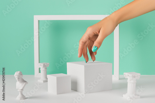 Womans hand podium and frame over turquoise background