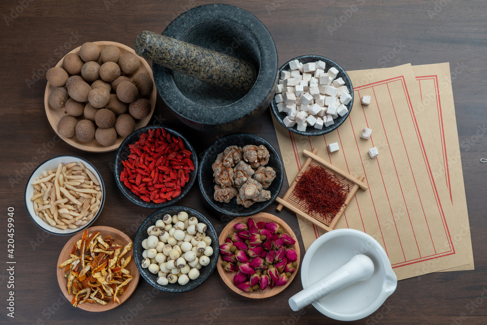 Ancient Chinese medicine books and herbs on the table