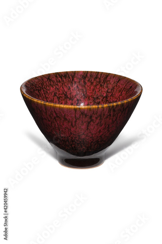 Subject shot of burgundy ceramic bowl with glazed surface and traditional Chinese tianmu pattern. Simple conic tea bowl is isolated on the white background. photo