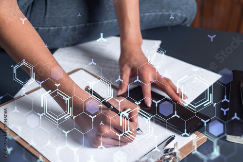 A businesswoman in casual wear writing down some ideas using phone to create innovative software to provide a completely new high-tech service. Close up shot. Hologram tech graphs. Concept of Dev team