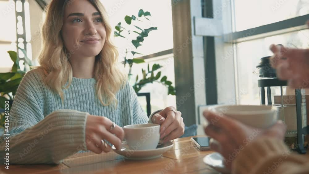 Young female friends talking and having a cup of tea and a coffee. Close-up. Young female friends talking and having a cup of tea and a coffee. Close-up.