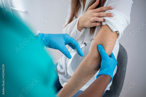 Woman is receiving a Covid-19 vaccination in doctor s office from nurse or doctor.  Woman Receiving Covid-19 Vaccine Injection In Clinic Room.  Covid 19 Population Immunization Campaign. Panorama