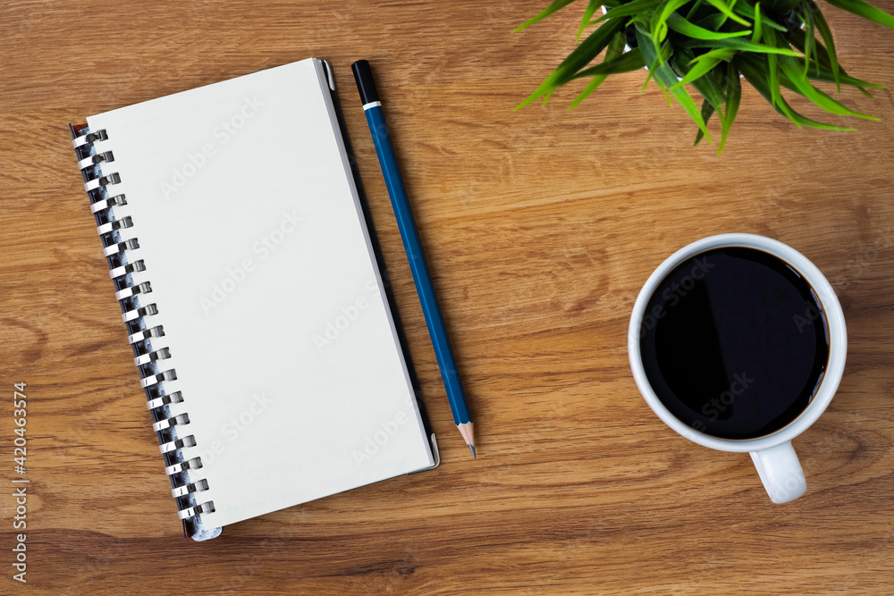 Top view of open school notebook with blank pages, coffee cup and pencil for taking write notes on table background. Flat lay, creative workspace office. Business-education concept with copy space. Top view of open school notebook with blank pages, coffee cup and pencil for taking write notes on table background. Flat lay, creative workspace office. Business-education concept with copy space.