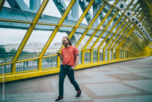 Bright young man with earphones listening to music in pedestrian bridge