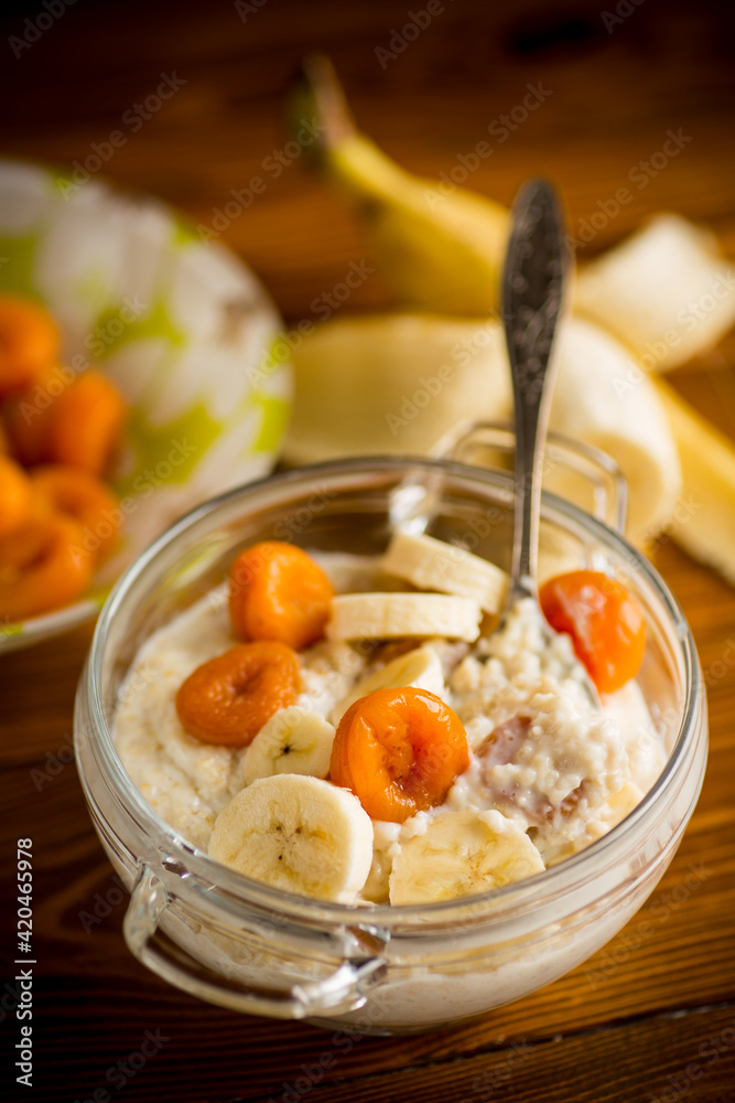 cooked boiled sweet oatmeal with with dried apricots and bananas in a bowl cooked boiled sweet oatmeal with with dried apricots and bananas in a bowl