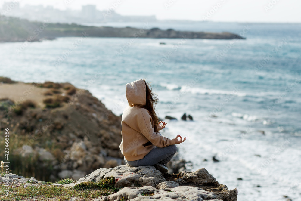 Young yoga woman meditation, mindfulness on seaside rock cliff edge. Beautiful sea view
