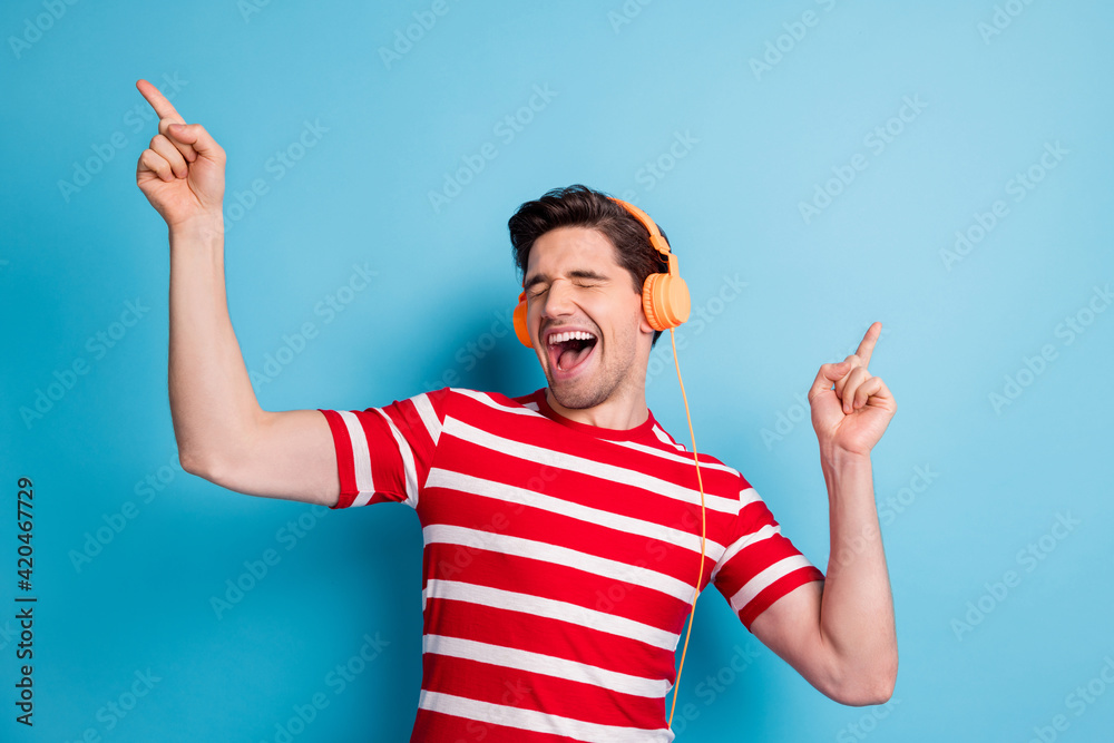 Photo portrait of male singer wearing orange earphones dancing singing enjoying music isolated on vibrant blue color background