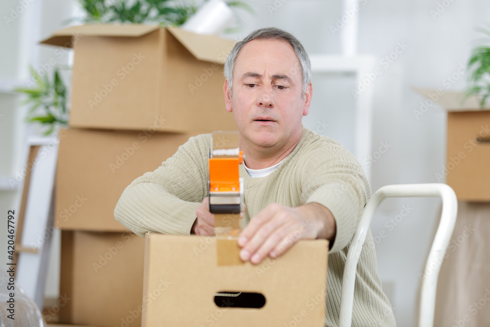 mature man using duct tape for packing stuff in box mature man using duct tape for packing stuff in box