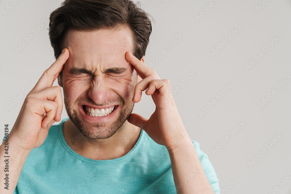 Stressed upset man suffering from a strong migraine Stressed upset man suffering from a strong migraine