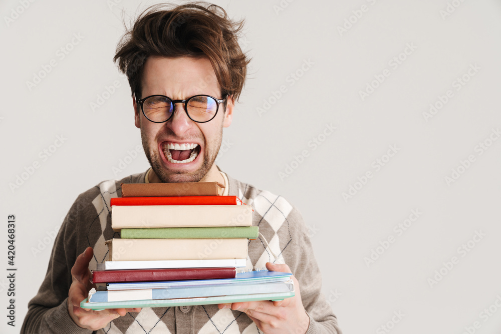 Shocked nerdy man holding stack of books isolated Shocked nerdy man holding stack of books isolated