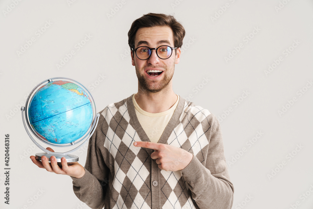 Geeky hipster pointing at globe smiling at camera Geeky hipster pointing at globe smiling at camera