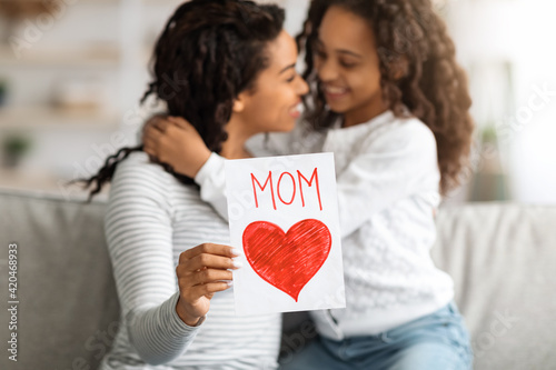 Cheerful black girl with gift card hugging her mom